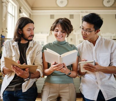 Group of young multinational students happily studying with book together in library of university
